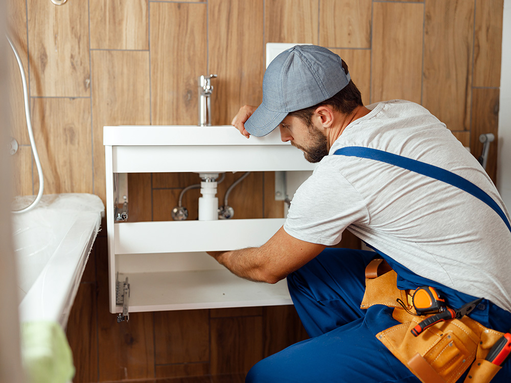 Handwerker repariert einen Waschtisch im Badezimmer als Hausmeisterservice und Schadensbeseitigung